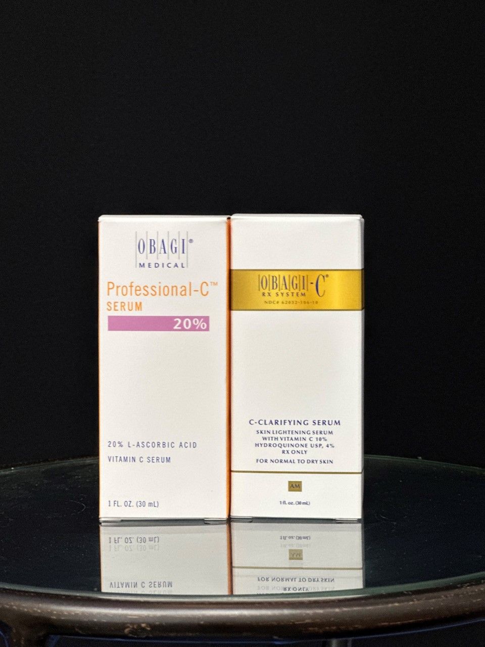 Two white boxes of Obagi Professional-C serum on a reflective surface against a dark background.