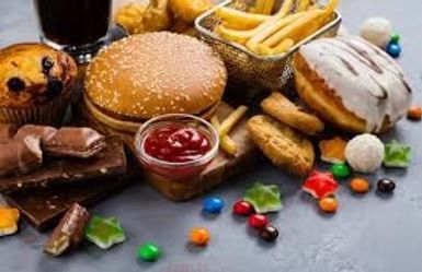 Assortment of unhealthy foods including a burger, fries, sweets, and soda.