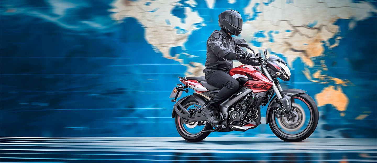 Uma pessoa em uma motocicleta vermelha contra um fundo de mapa-múndi desfocado.