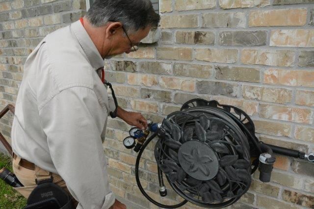 Man using a hose reel attached to a brick wall.