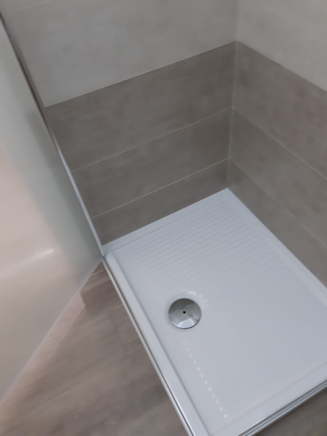 Un piatto doccia bianco è posizionato in un bagno accanto a una parete piastrellata.