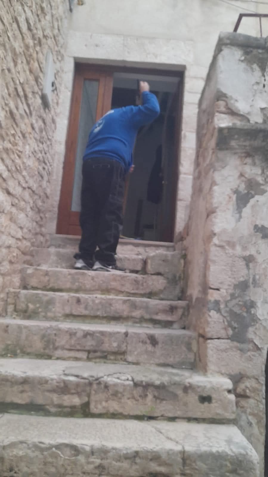 Un uomo con una felpa blu è in piedi su una rampa di scale.