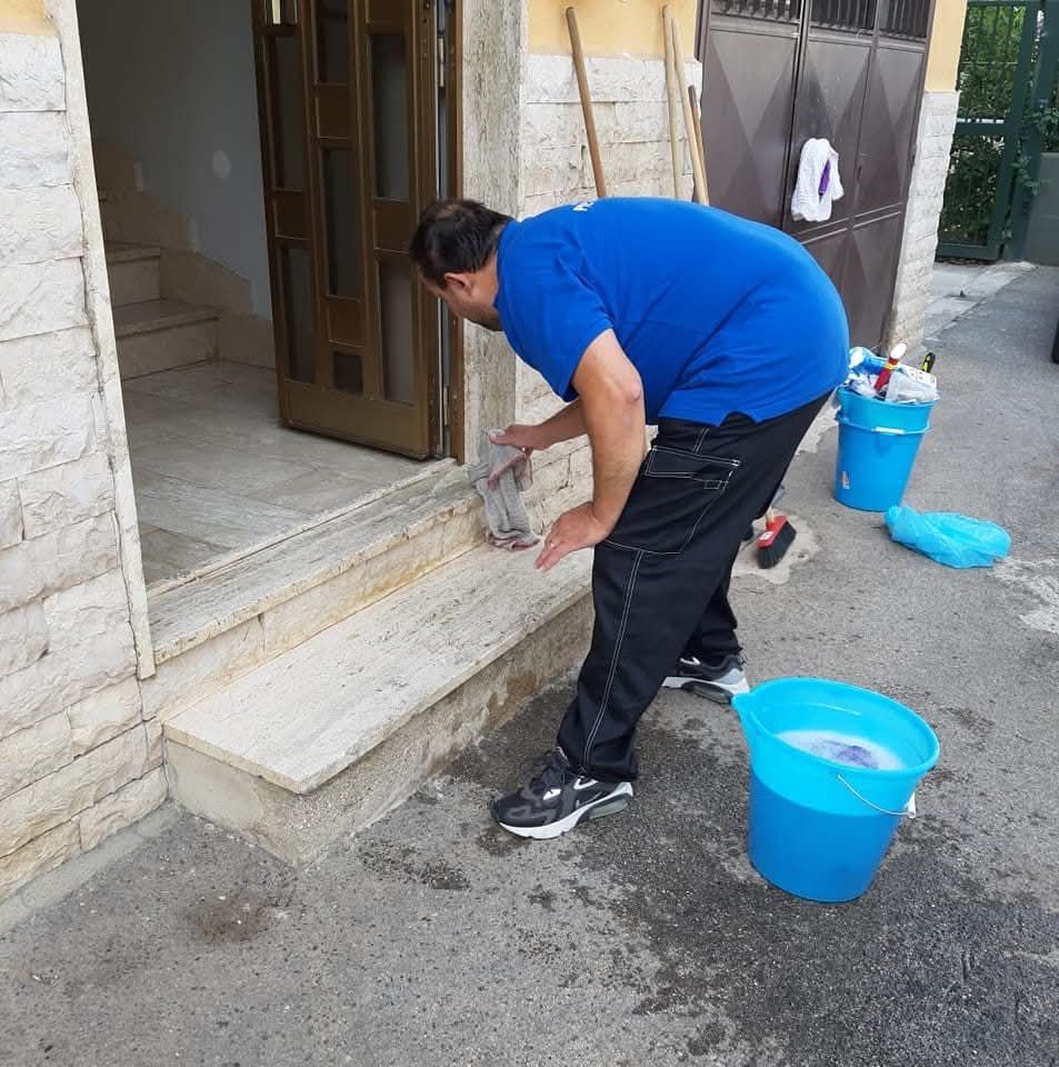 Un uomo con una camicia blu sta pulendo i gradini di un edificio