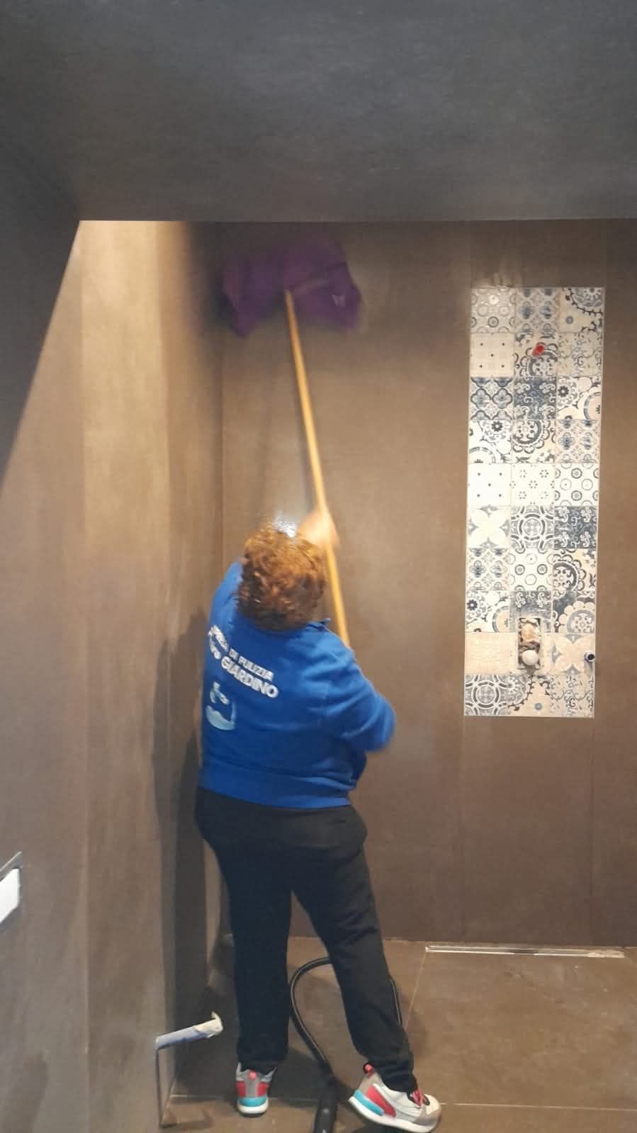 Una donna sta pulendo una stanza con uno straccio.