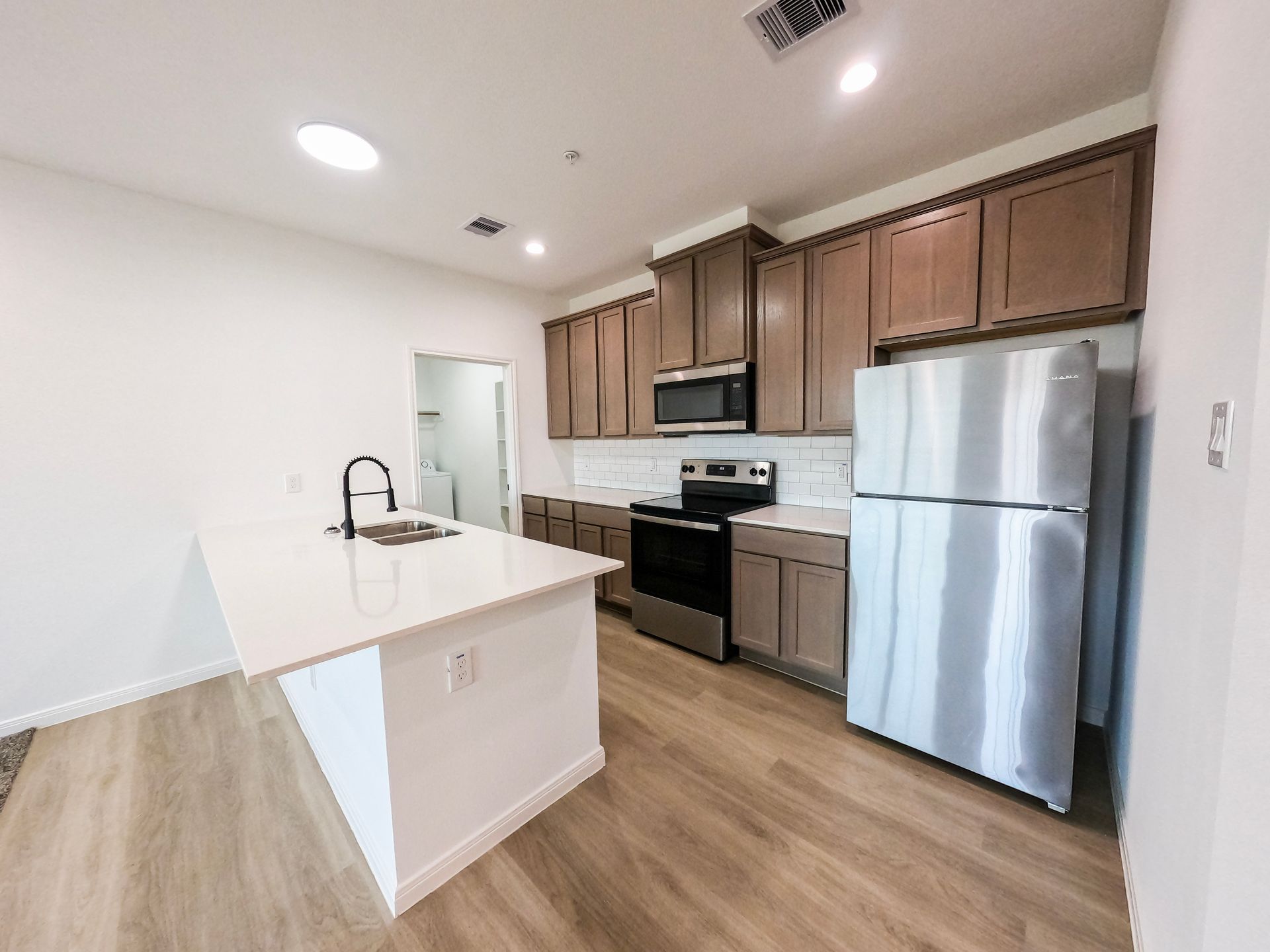 Modern kitchen with light wood cabinets, stainless steel appliances, and an island.