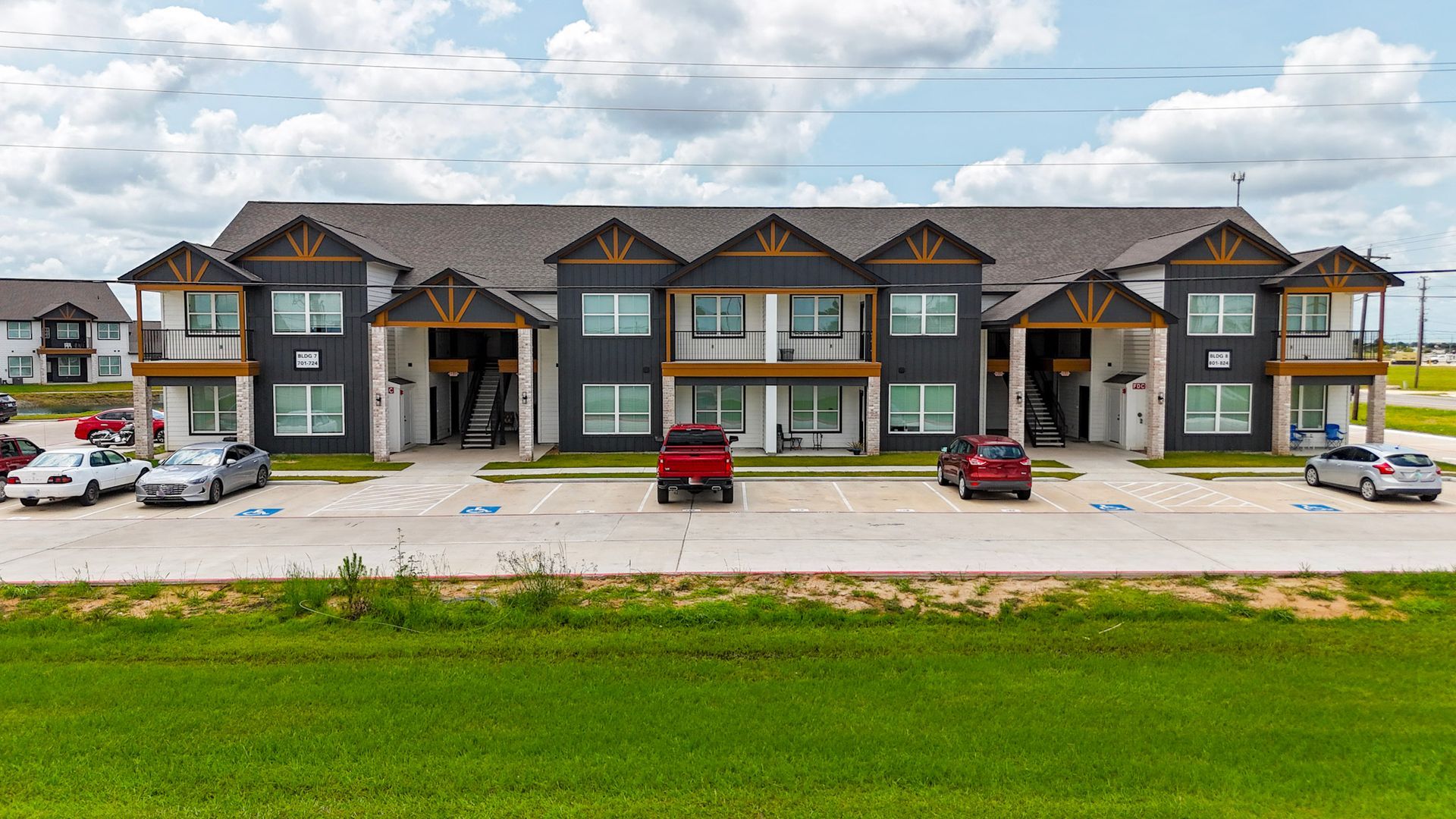 Row of townhomes next to a canal with a walking path, under a blue sky.