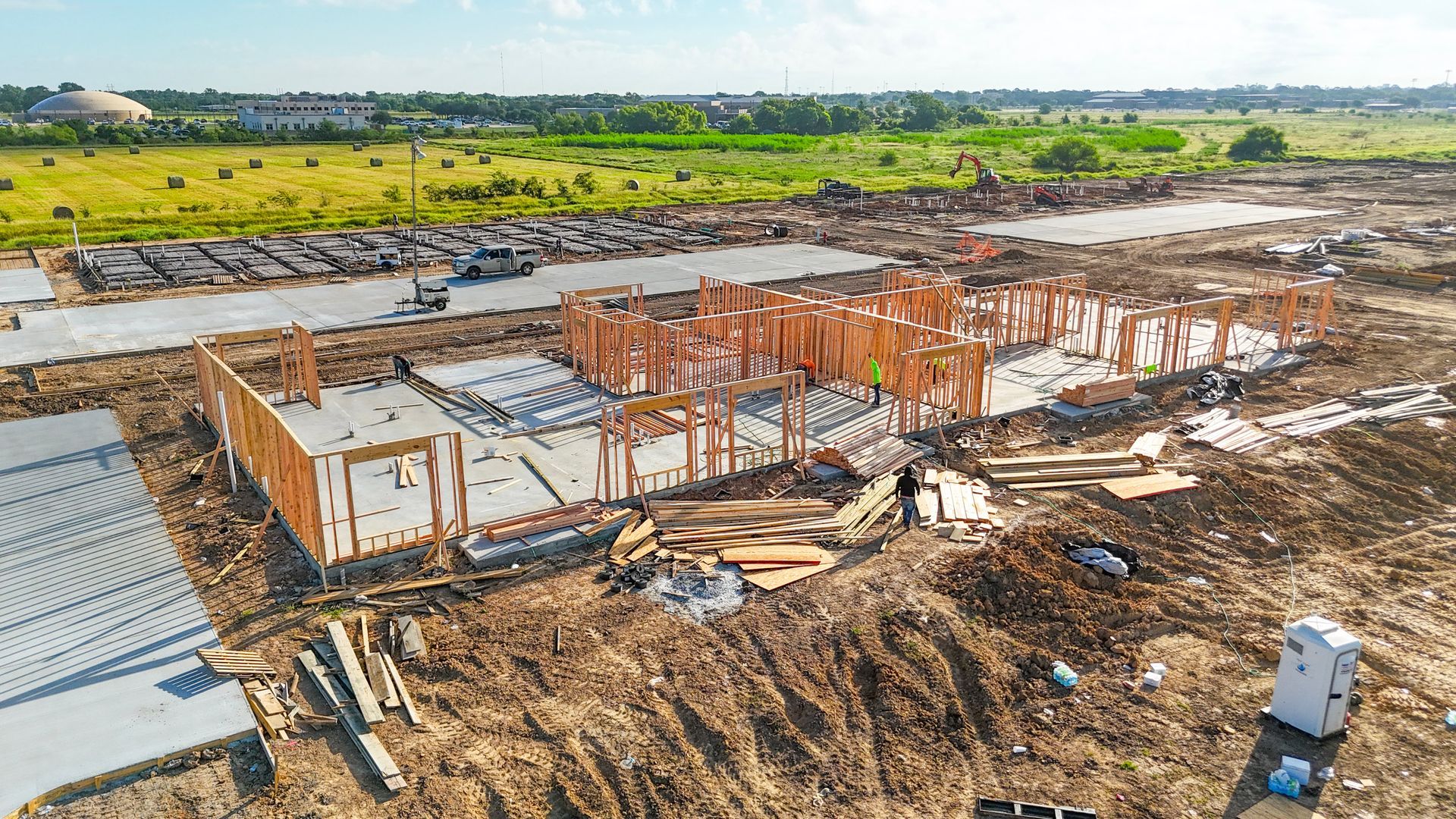 Construction site with wooden framing for a building. Dirt and construction materials surround the unfinished structure.