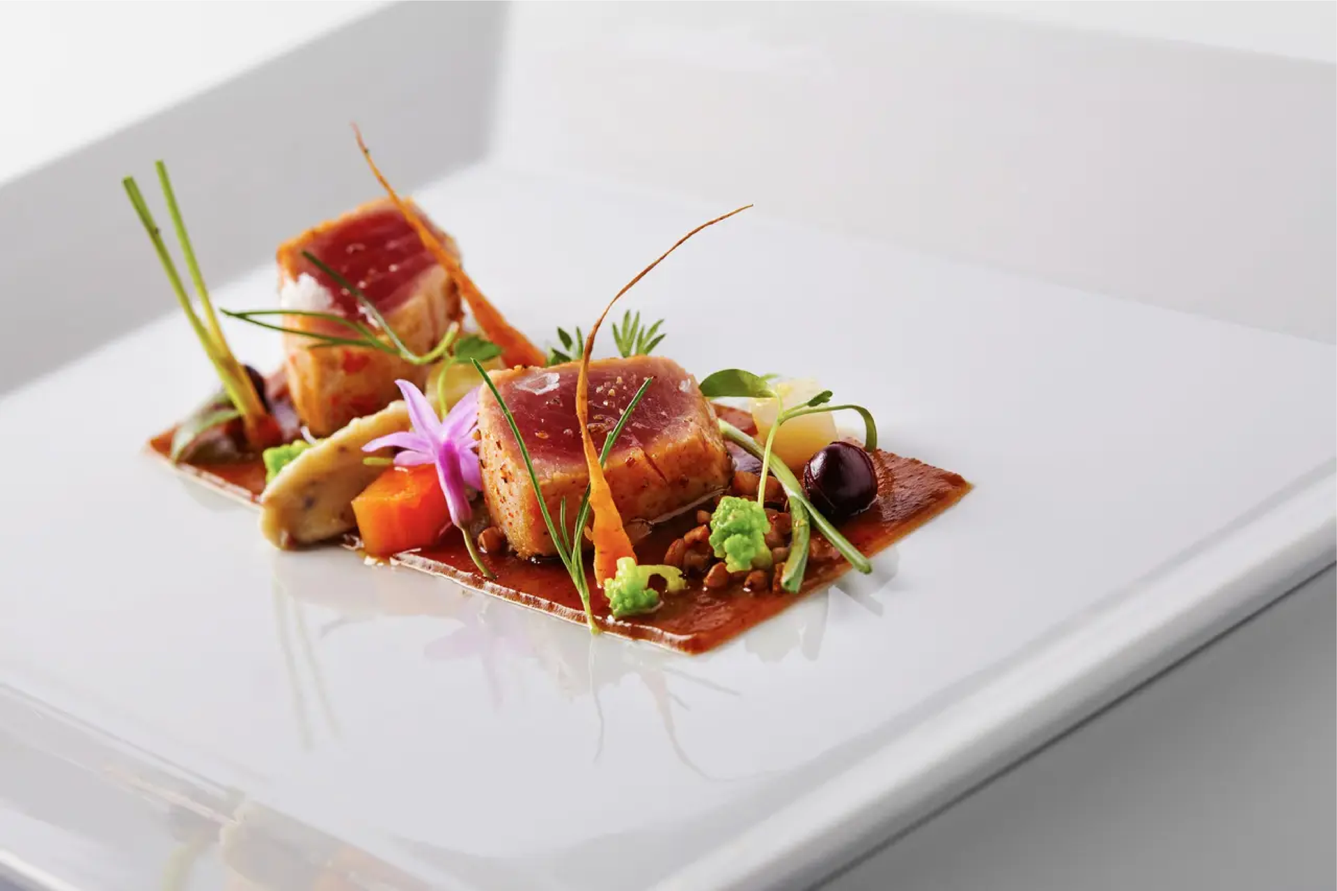Une assiette blanche garnie de viande et de légumes sur une table.