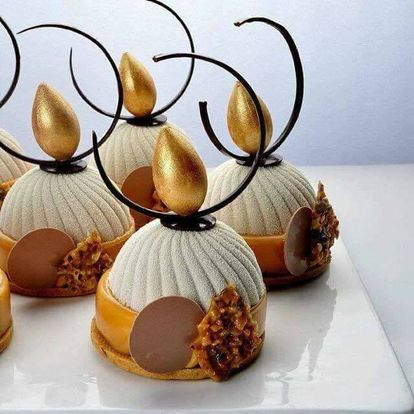 Une assiette blanche surmontée d'un bouquet de desserts aux décorations dorées