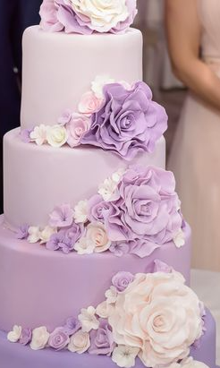 Un gâteau de mariage avec des fleurs violettes et blanches dessus.