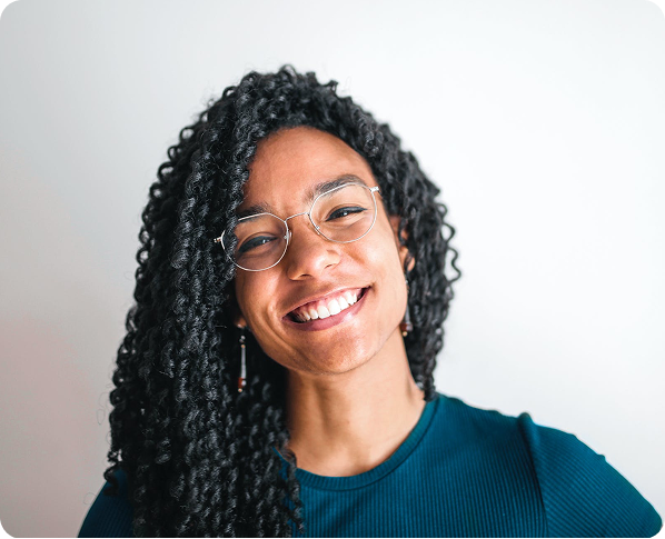 A woman with curly hair and glasses is smiling for the camera.