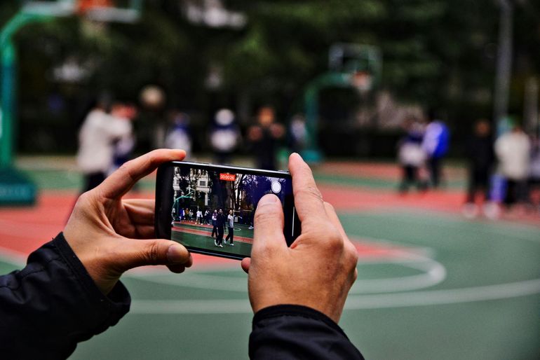 A person is taking a picture of a basketball court with a cell phone.