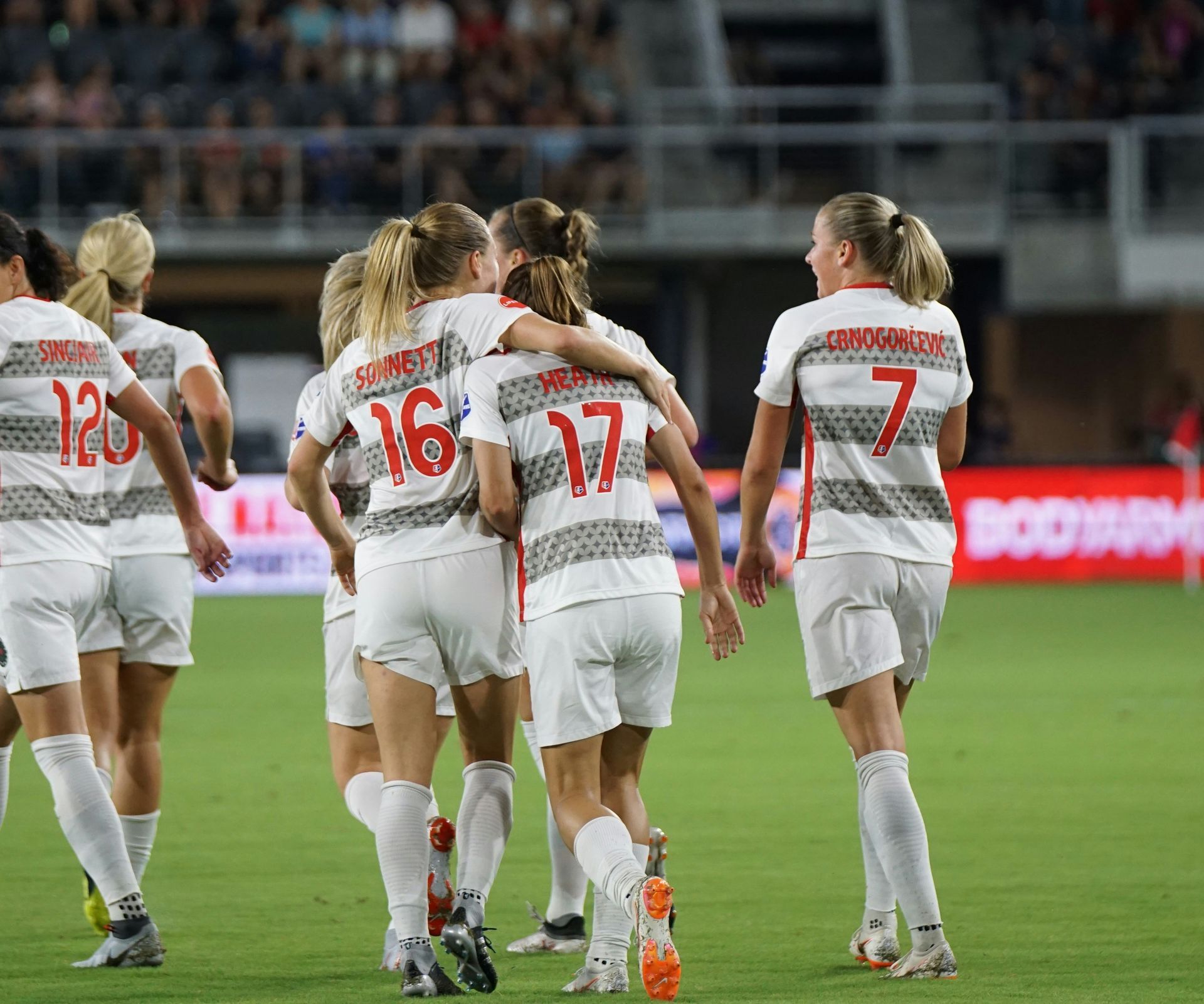 A group of female soccer players are huddled together on the field.