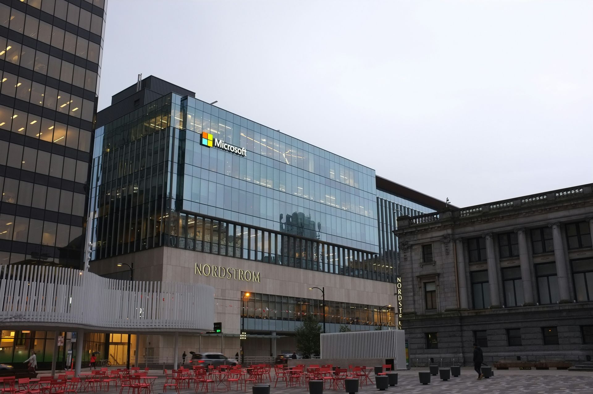Microsoft office building with glass facade, next to a historic building, in an urban setting.