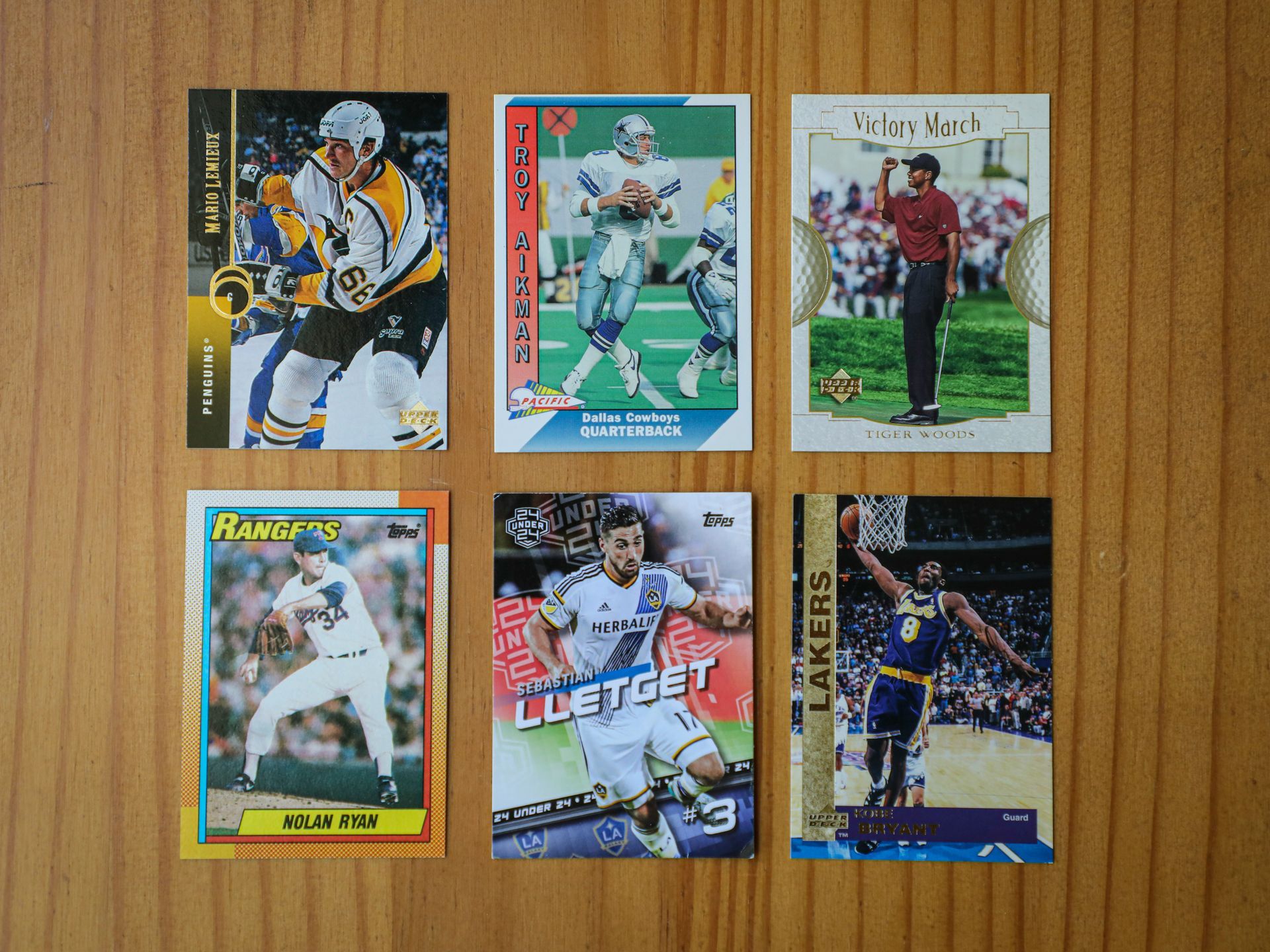 Six sports trading cards on a wooden surface, featuring hockey, football, golf, and basketball players.
