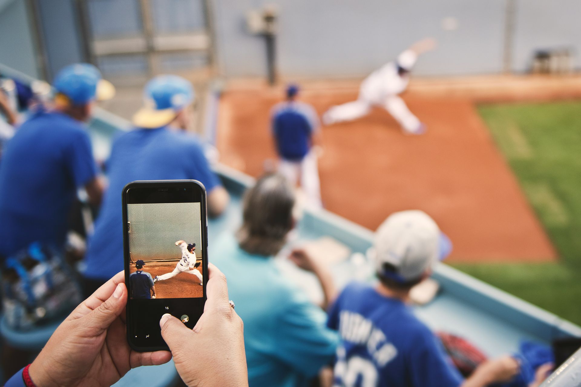 A person is taking a picture of a baseball game with a cell phone.