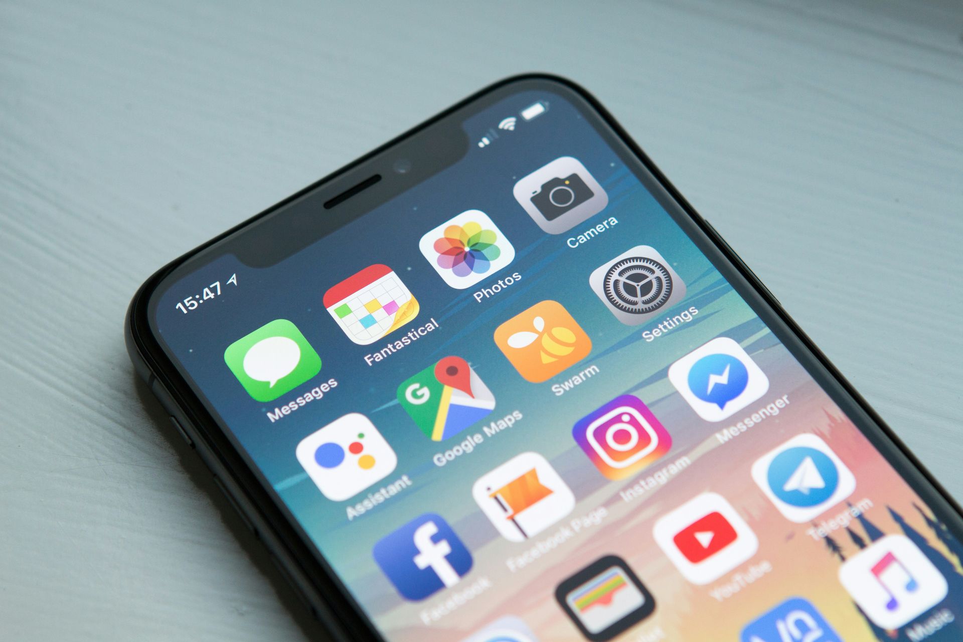 Close-up of a smartphone displaying various app icons on a blue home screen.