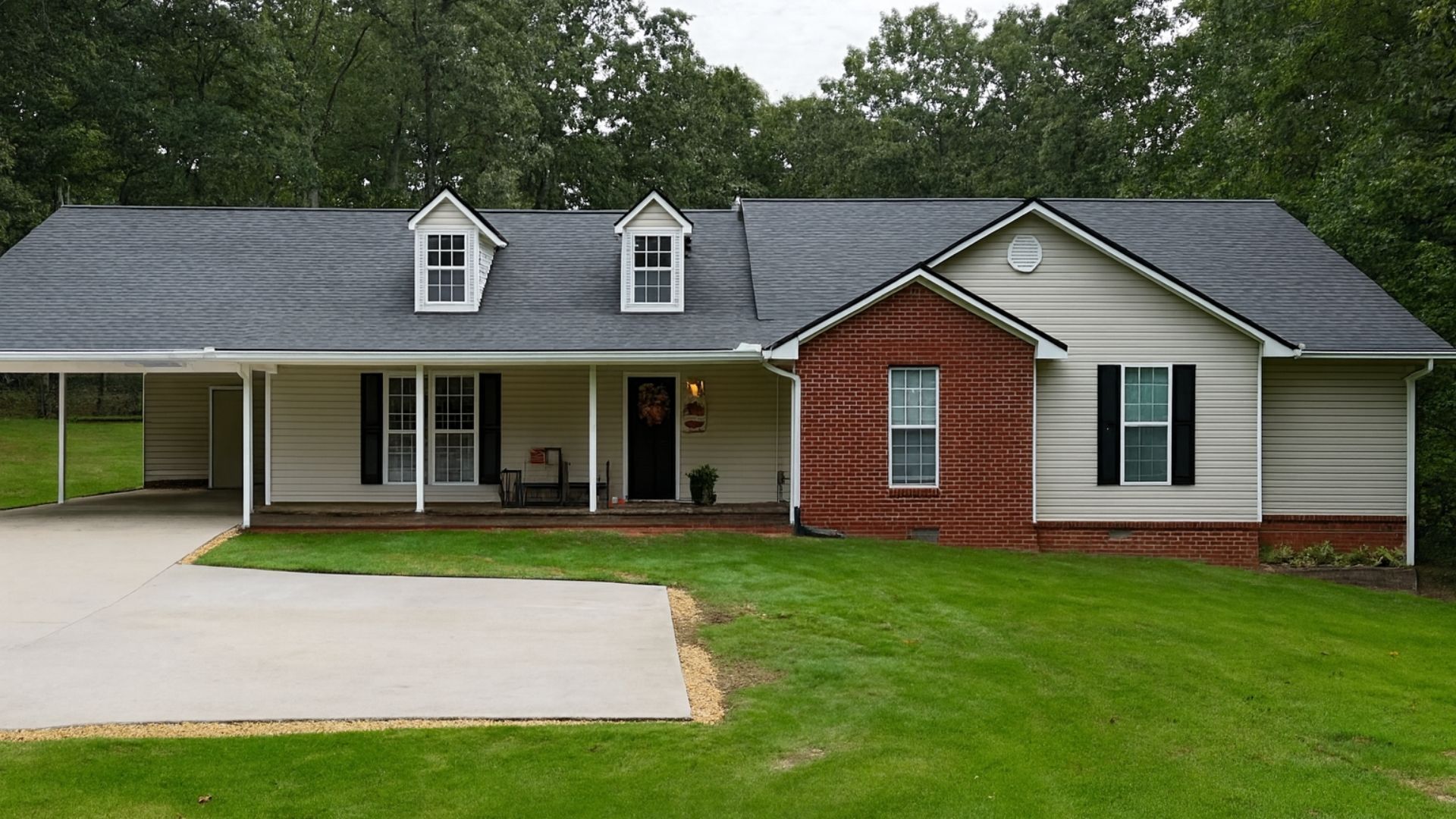 Ranch-style house with a carport, brick accents, and a green lawn. Overcast day.