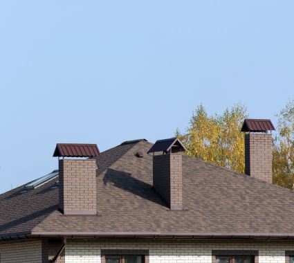 There are two chimneys on the roof of a house.