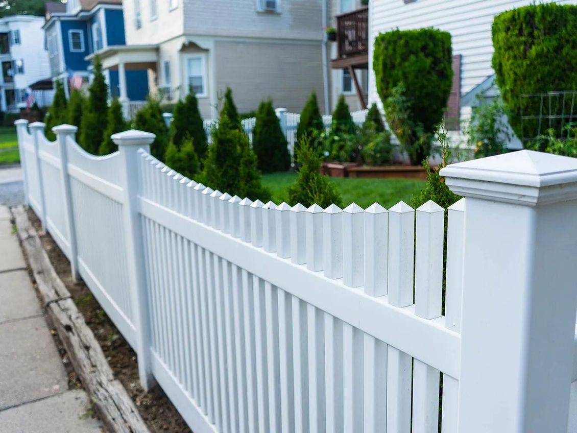 A white picket fence in Carrollton Ga surrounds a lush green yard in front of a house.