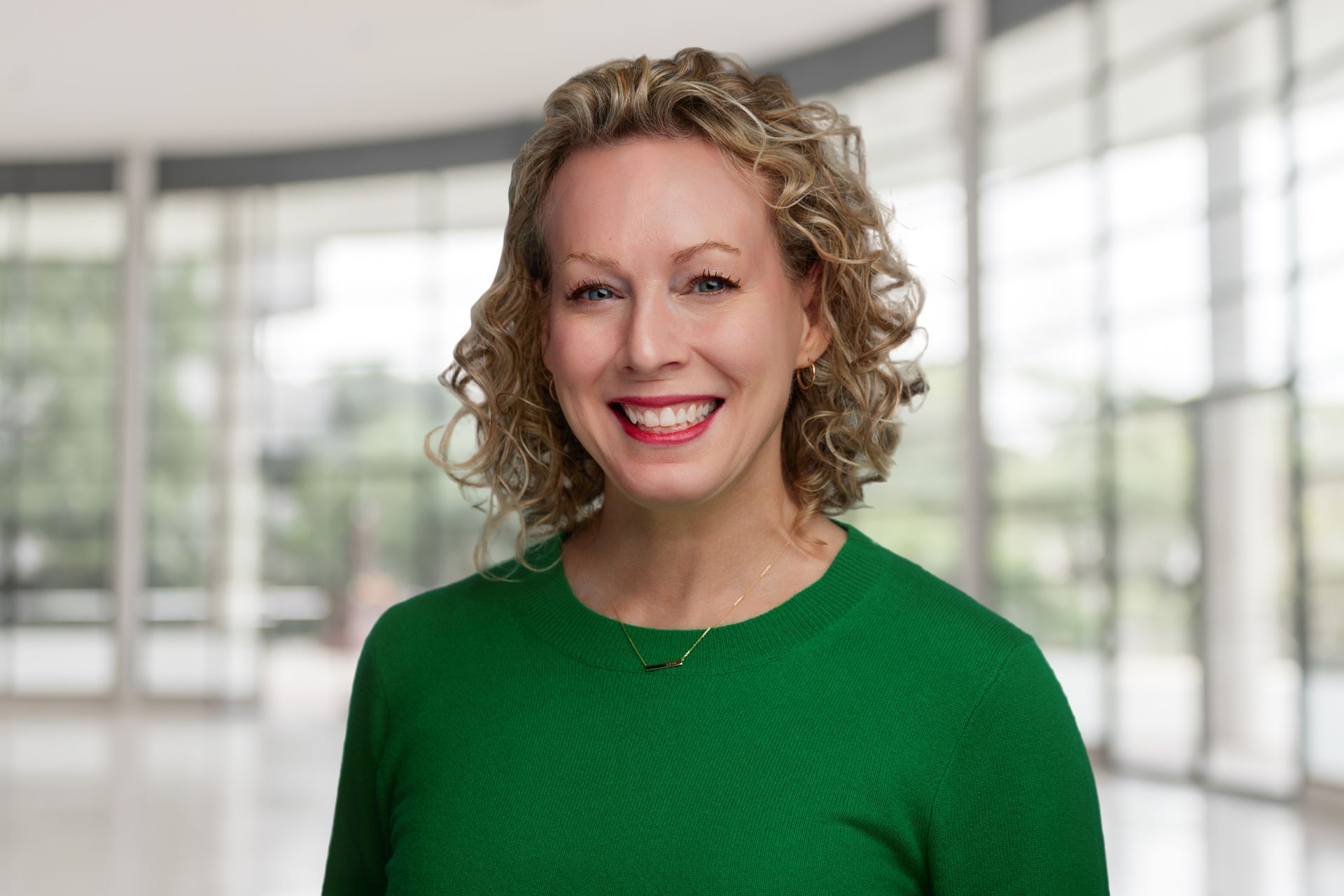 The woman is wearing a pink shirt and smiling for the camera.