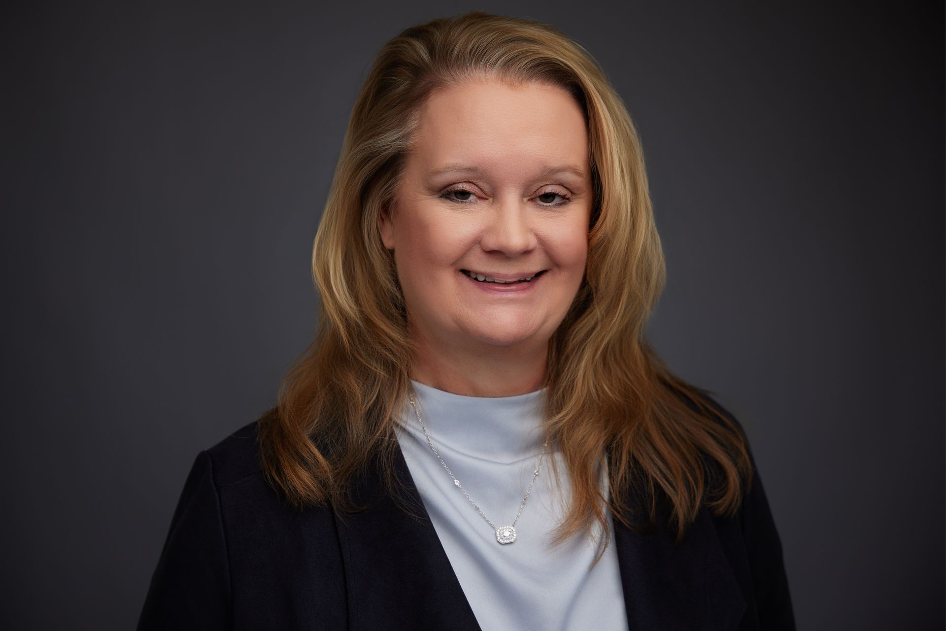 A woman in a blue jacket is smiling for the camera.