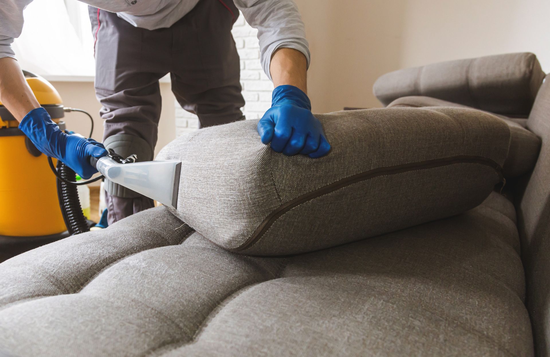 A partial view of a man cleaning a sofa by a professional extraction method. A partial view of a man cleaning a sofa by a professional extraction method.