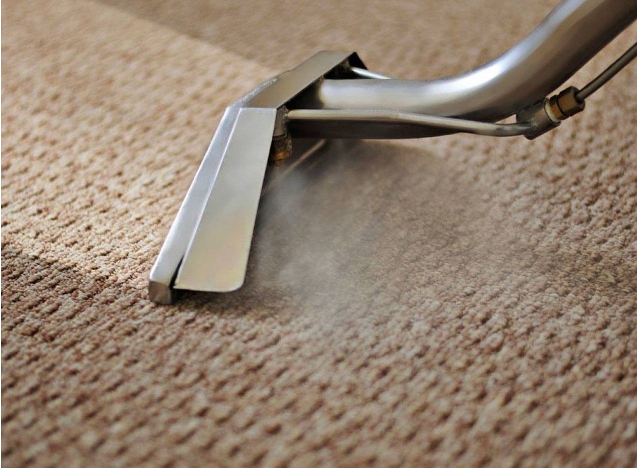 Carpet cleaner nozzle steaming a light brown carpet.