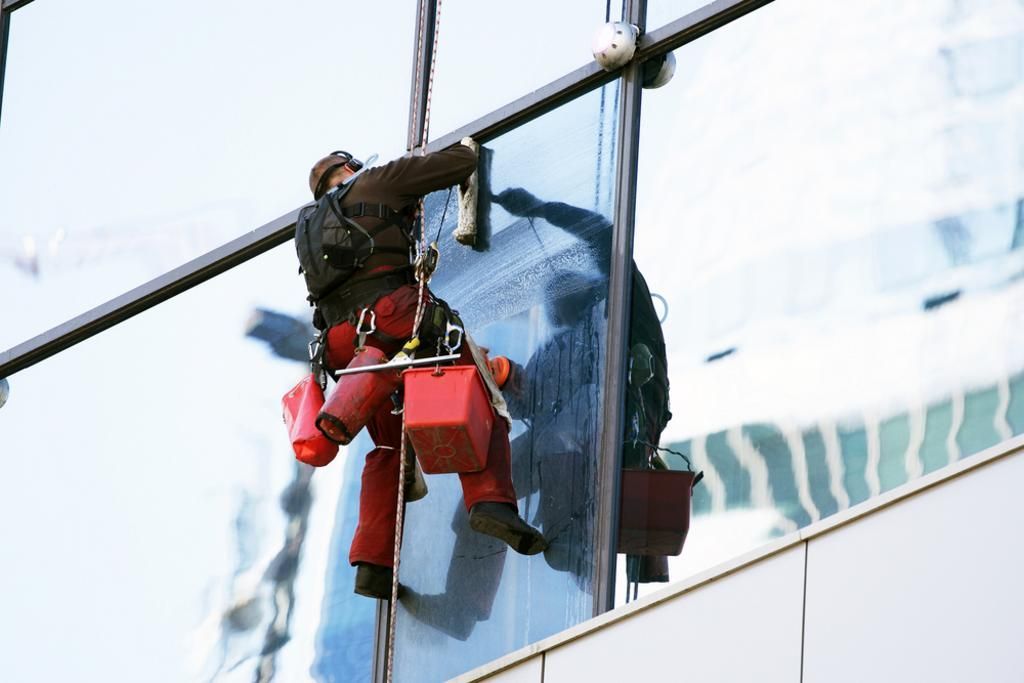 A woman is cleaning a window in a living room.