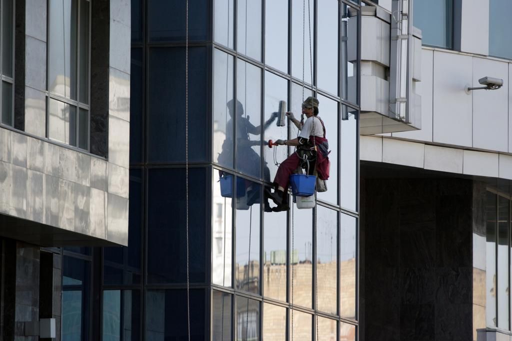 A man is cleaning the windows of a tall building.