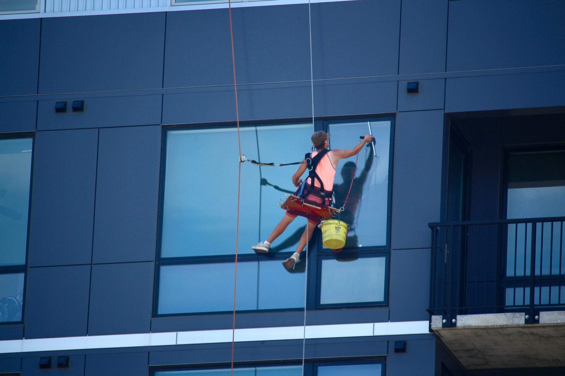 A woman is cleaning the windows of a tall building.