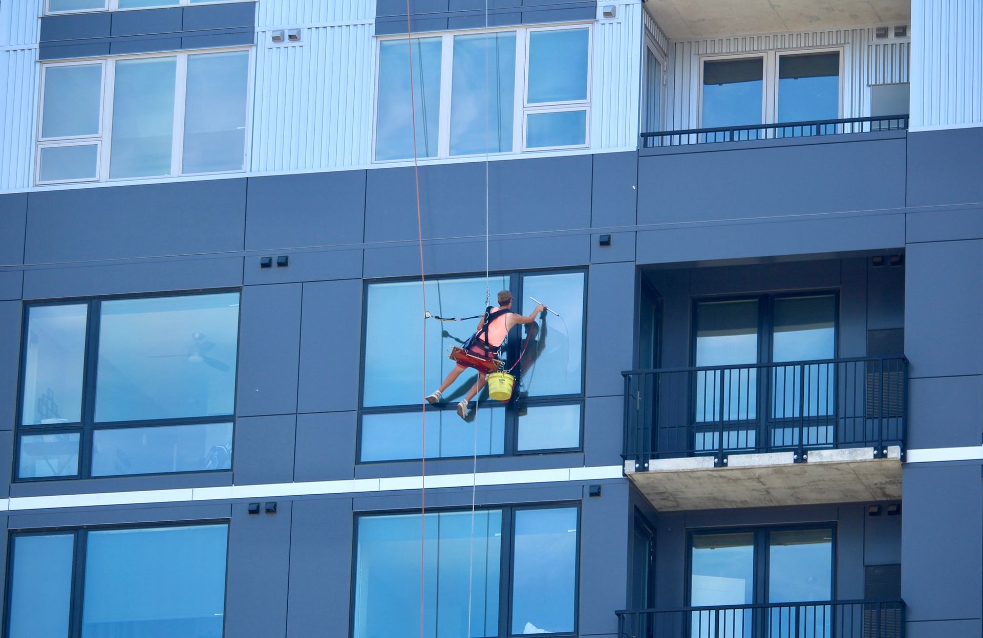 A man is cleaning the windows of a tall building.