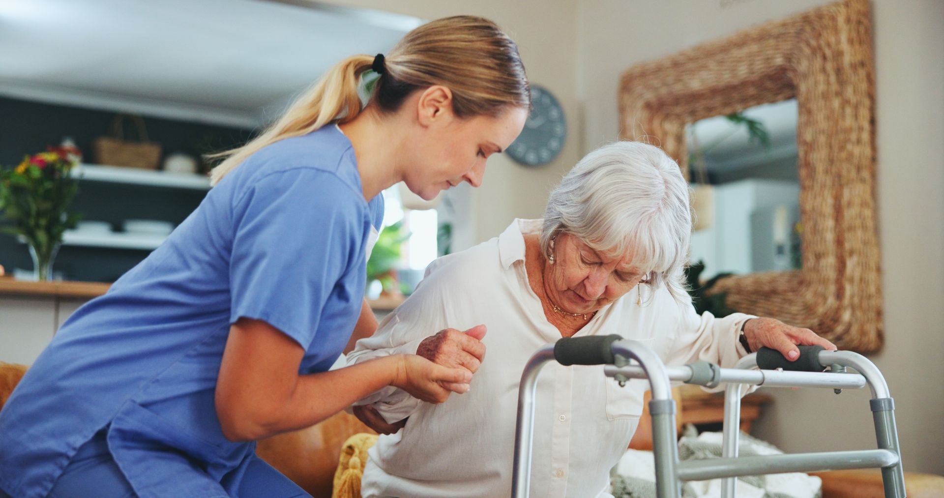 A nurse is helping an elderly woman use a walker.