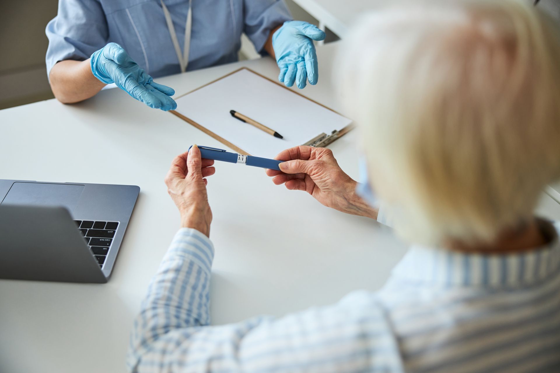 An elderly man is sitting at a table with a nurse.