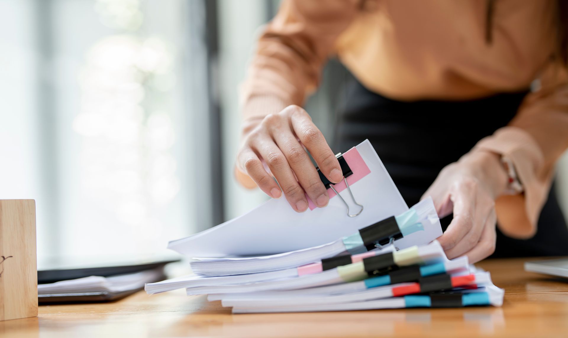 A woman is holding a piece of paper over a stack of papers.