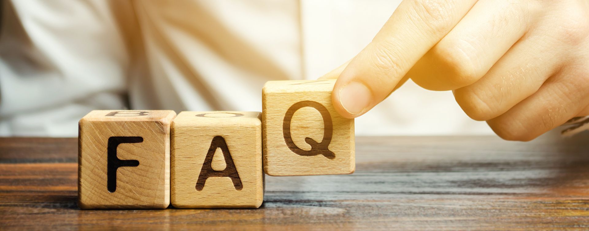 A person is holding a wooden block with the word faq written on it.