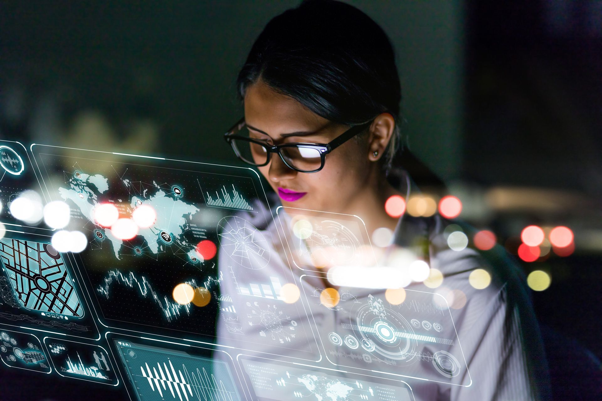 A woman wearing glasses is sitting in front of a laptop computer.