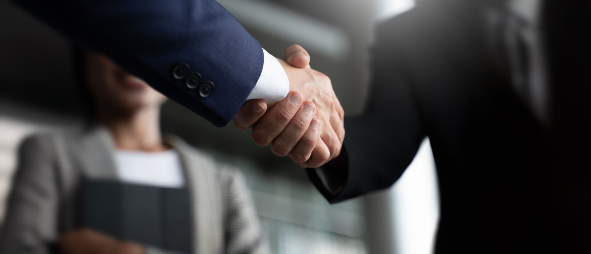 A man and a woman are shaking hands in an office.