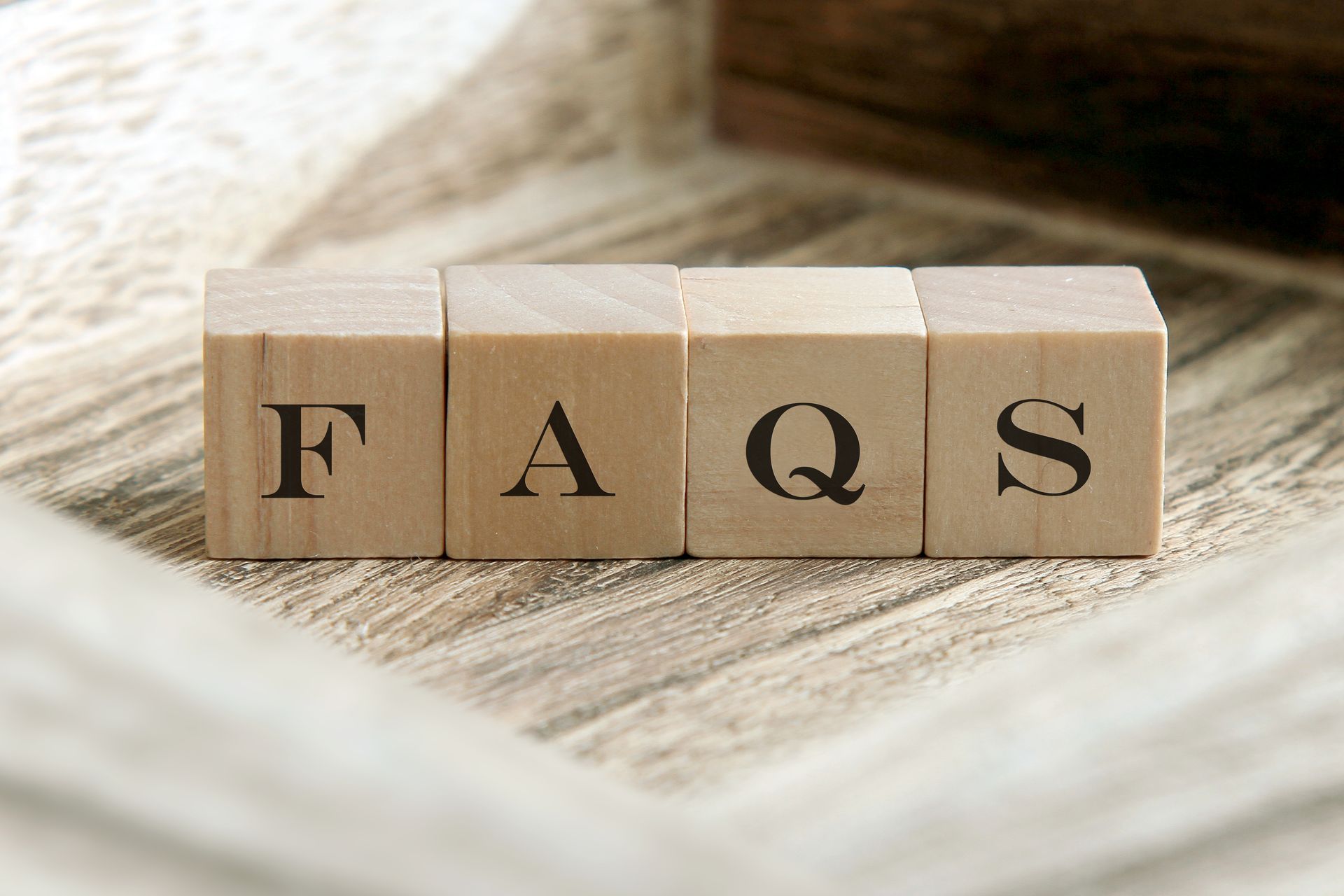 The word faqs is written on wooden blocks on a wooden table.