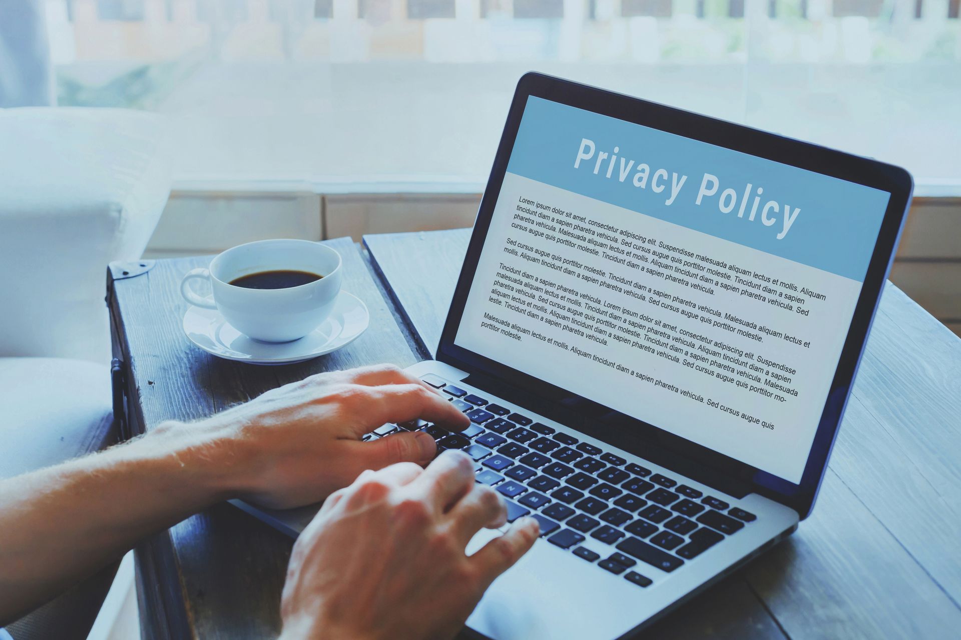 A person is typing on a laptop with a privacy policy on the screen.