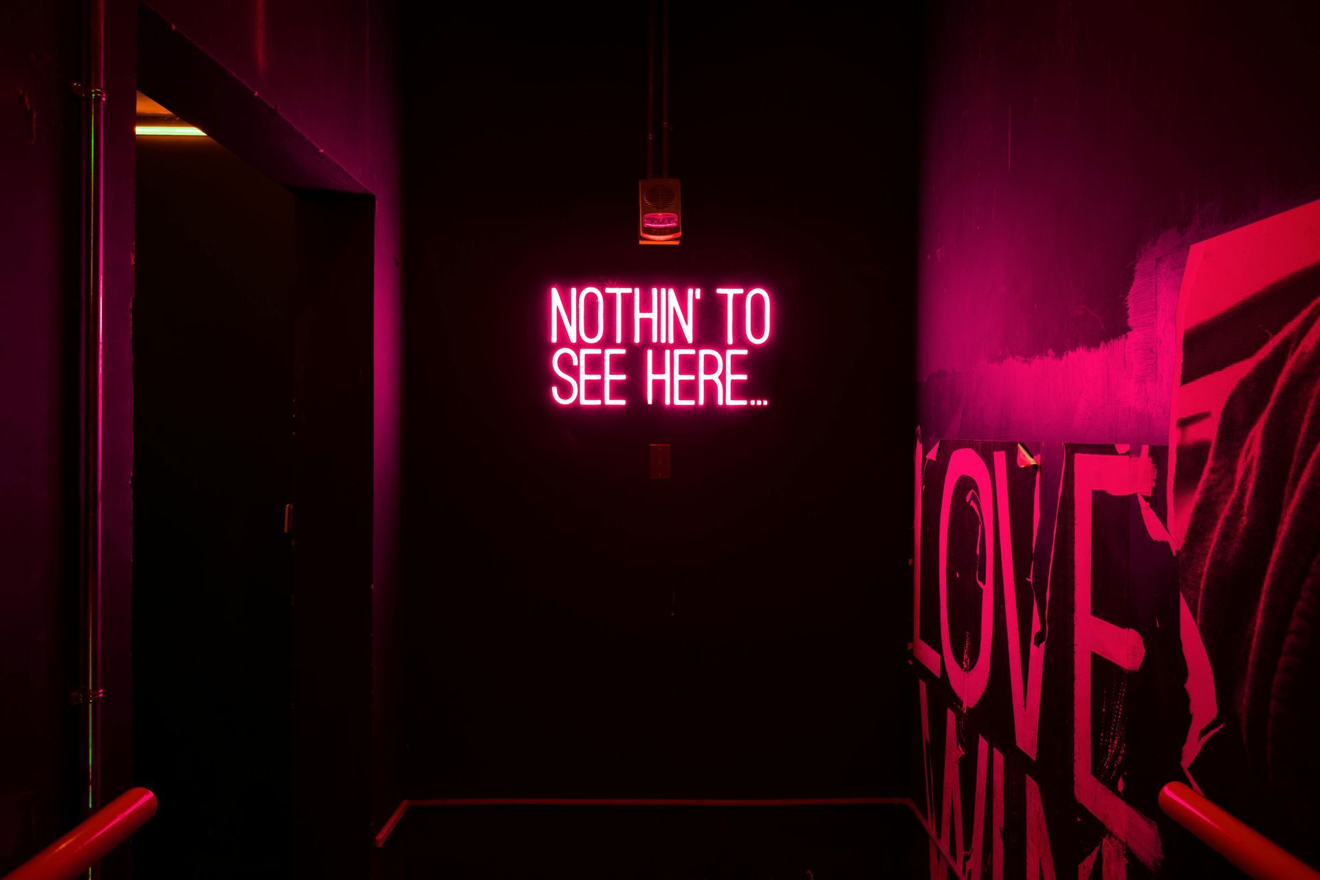 A hallway with a neon sign that says