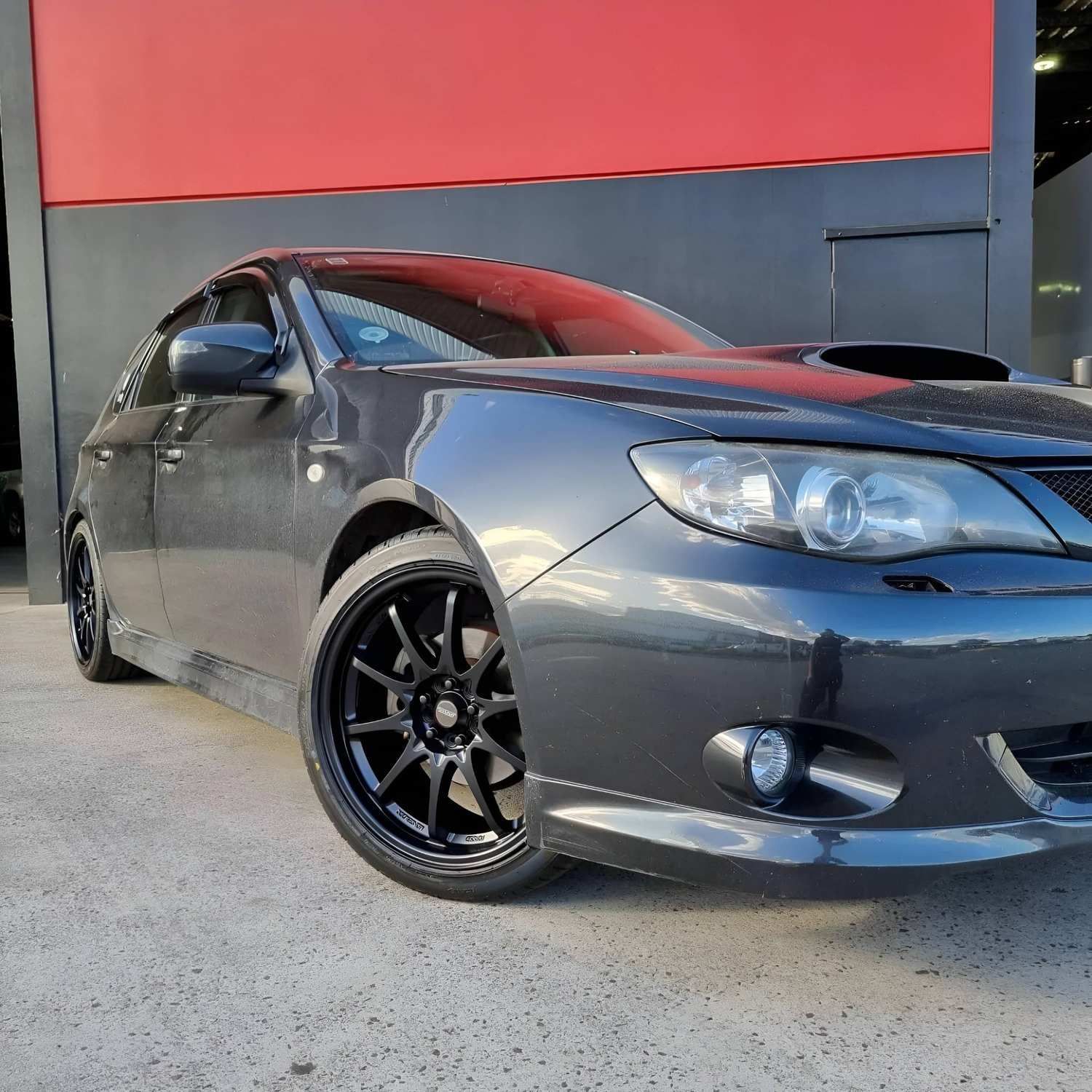 A Black Car is Parked in Front of a Red and Black Building — Stamford Tyres In Ballarat Central, VIC