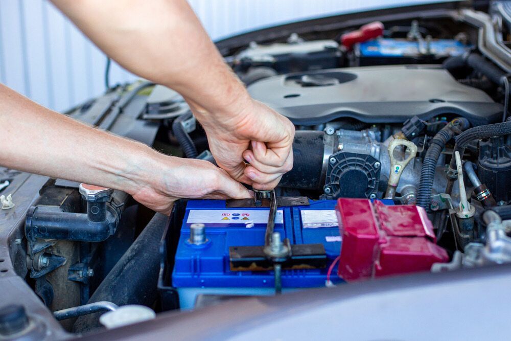 A Man is Fixing a Car Battery With a Wrench — Stamford Tyres In Ballarat Central, VIC