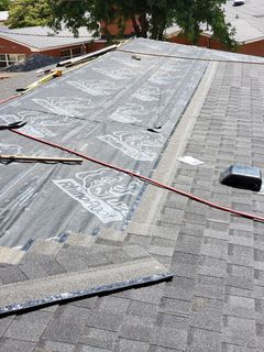 The roof of a house is being repaired and covered with a tarp.