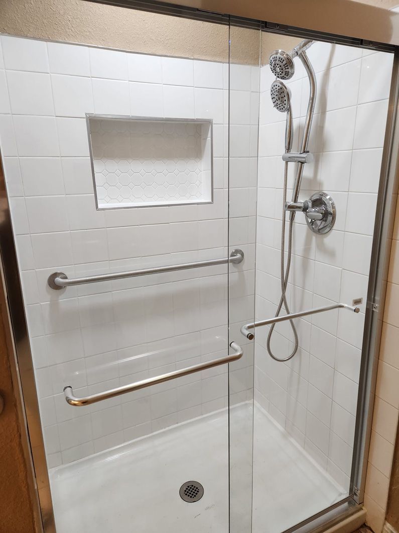 A shower with a sliding glass door and a shower head.