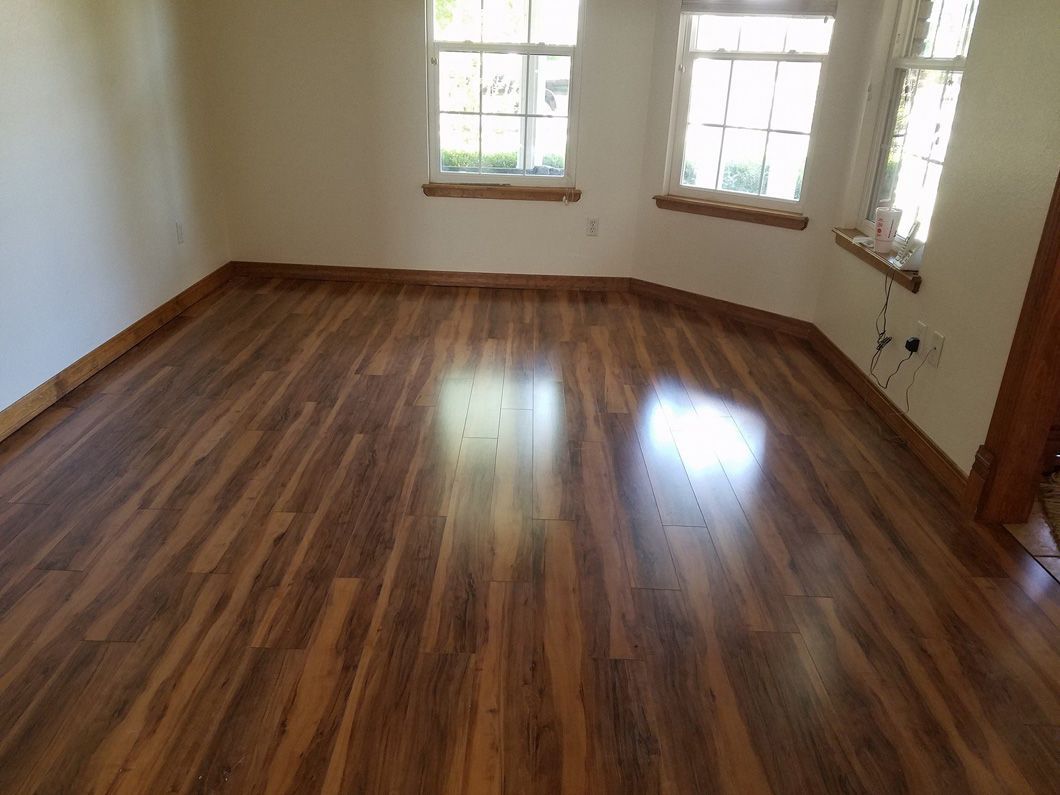 An empty room with a wooden floor and two windows.