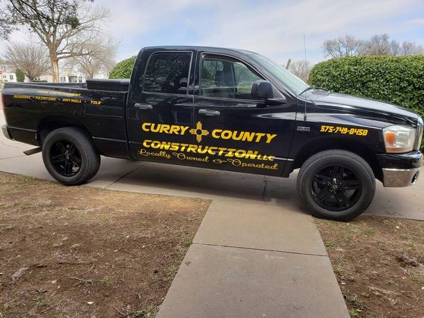 A black county construction truck is parked on a sidewalk.