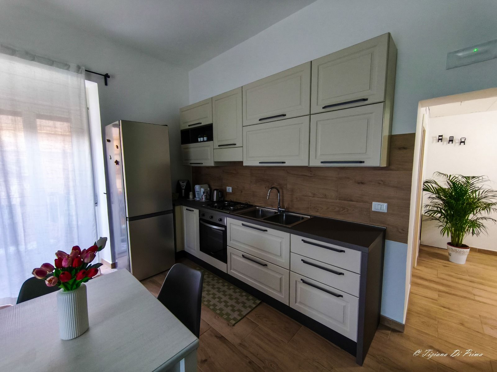 Una cucina con tavolo, sedie e un vaso di fiori sul bancone.