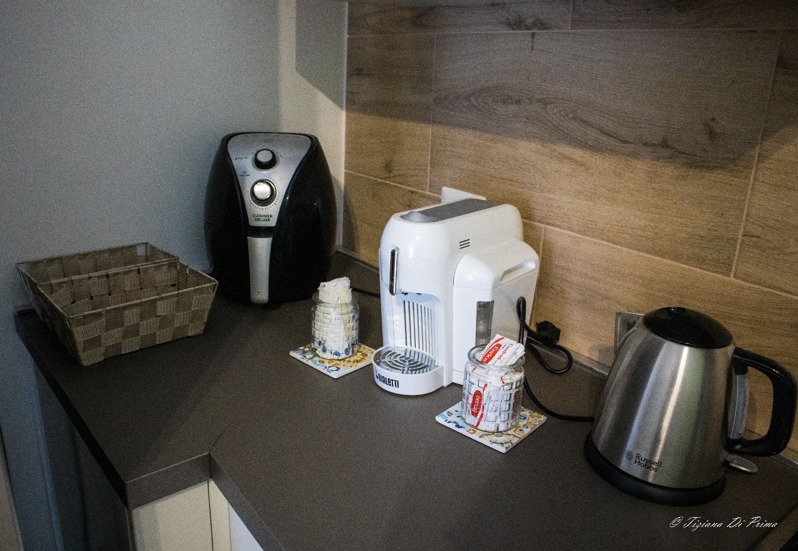 Un bancone da cucina con macchina per il caffè, tostapane e bollitore.