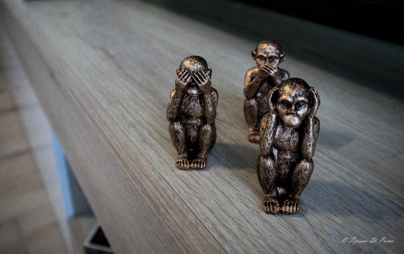 Tre statue di scimmie sono sedute su un tavolo di legno.